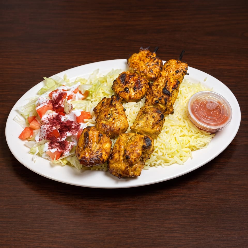 Chicken shish tawook skewers with rice, salad, and a side of red sauce on a white plate.